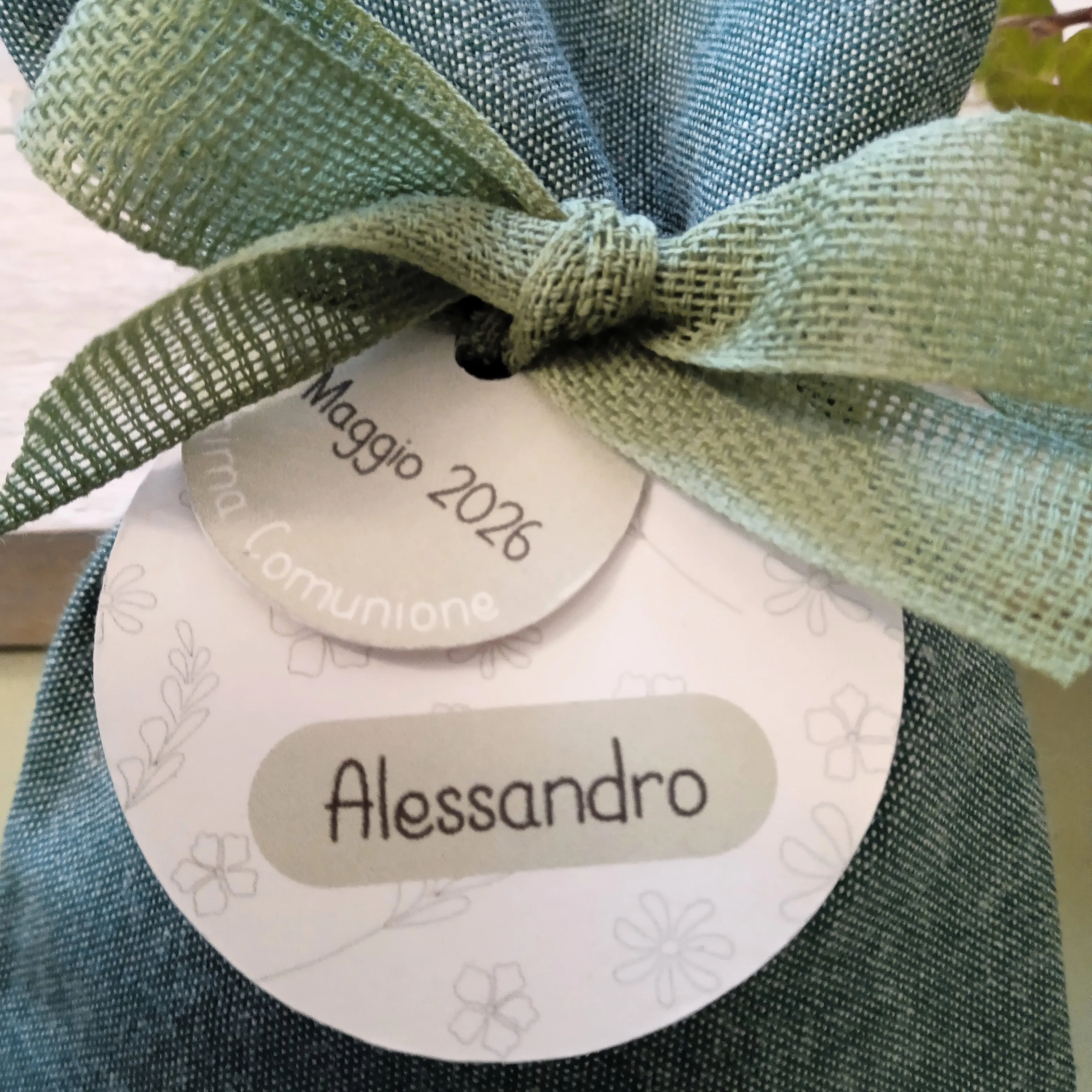 Dettaglio del doppio tag personalizzato con grafica a fiorellini e tag verde salvia