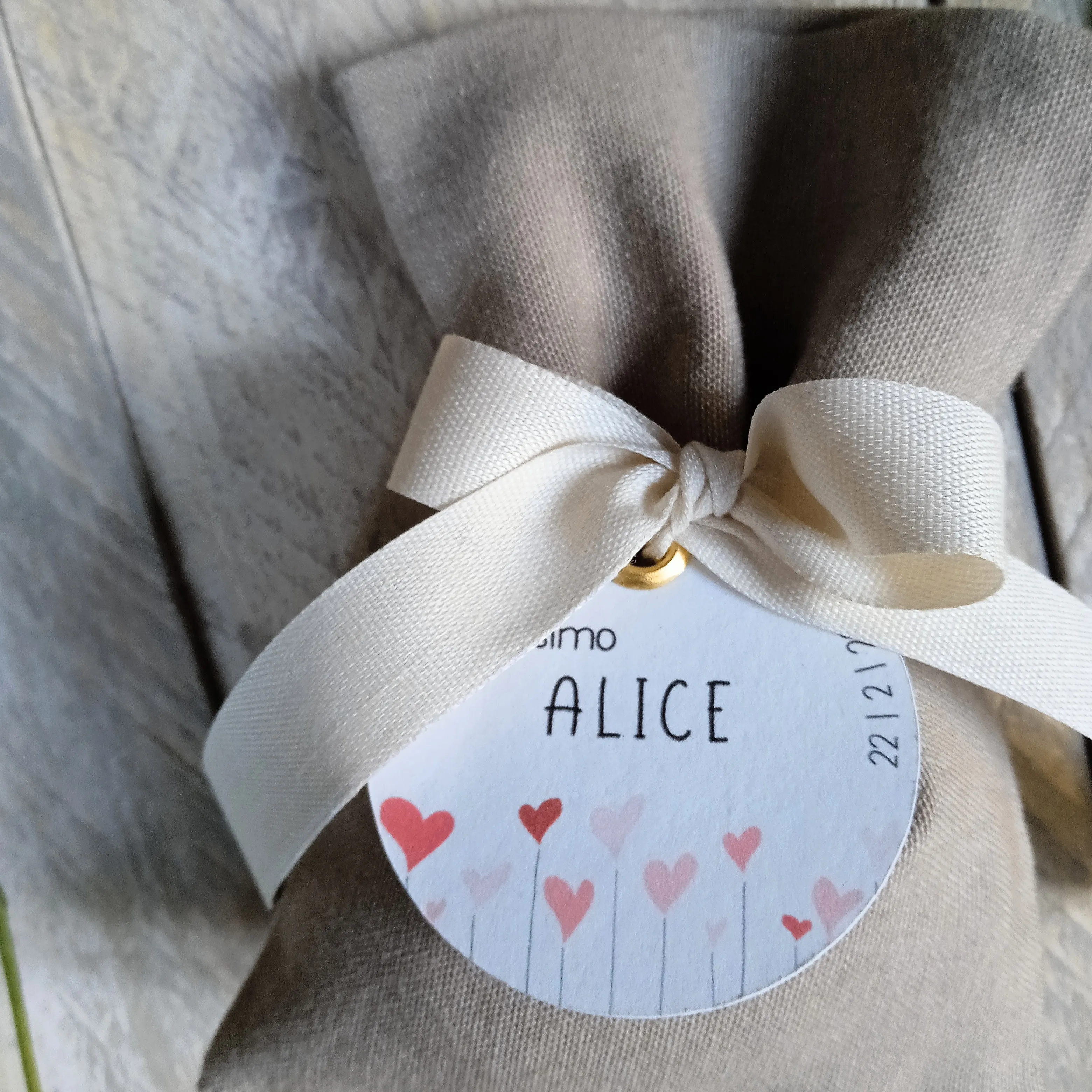 Dettaglio del tag personalizzato con grafica Cuoricini e nastro in cotone color beige